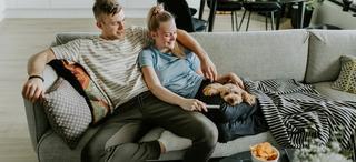 Ungt par med hund slapper av i sofa